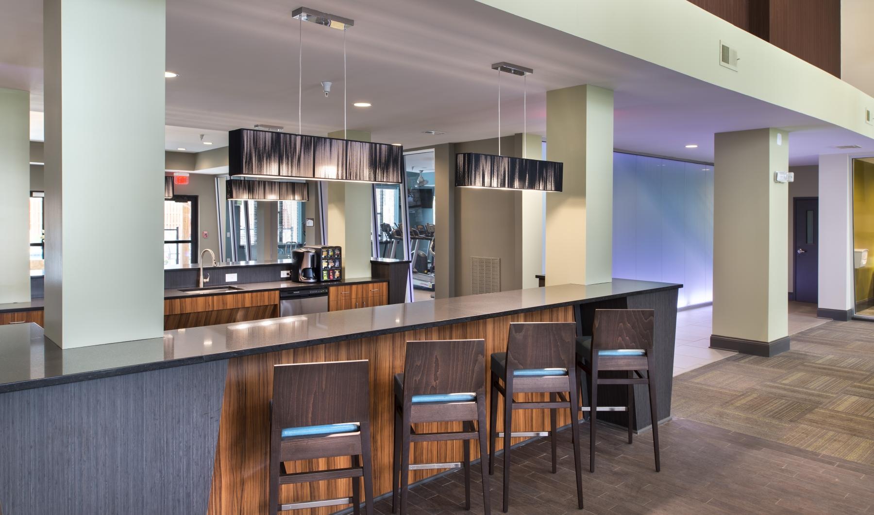 Quick access to state-of-the-art amenities a large kitchen with a bar and chairs
